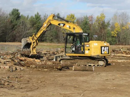 Excavator picking up and moving logs that will be used for future 2 CER operations // Une excavatrice ramasse et déplace des troncs d’arbres qui serviront lors d’opérations futures du 2 RGC