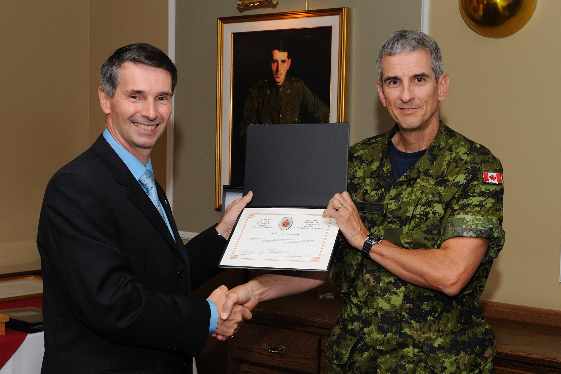 Capt Jacques Landry accepts certificate from MGen Dan Benjamin