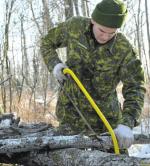 Private Seldong Neustaeter cuts logs to length for the roof of his improvised shelter during Exercise SURVIVING SAPPER in Cooking Lake, Alberta, from January 22-24,2016.