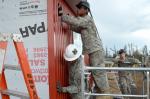 Soldiers with the 808th Engineer Company, Houston, TX, work together to secure siding to the gas hut they are building. PHOTO: Sergeant Crystal L Milton // Les soldats de la 808th Engineer Company de Houston, TX, travaillent ensemble pour sécuriser les côtés de la chambre à gaz qu’ils construisent.. Les soldats américains sont venus de plus de 10 états en août 2014 pour participer à cette opération. PHOTO : Sergent Crystal L Milton