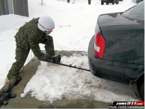 A sapper inspects the undercarriage of a vehicle for booby traps.