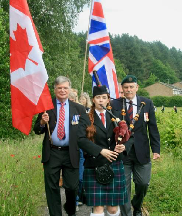 The official party led by Vince Larocque and Bill White followed by the public is piped to the ceremony