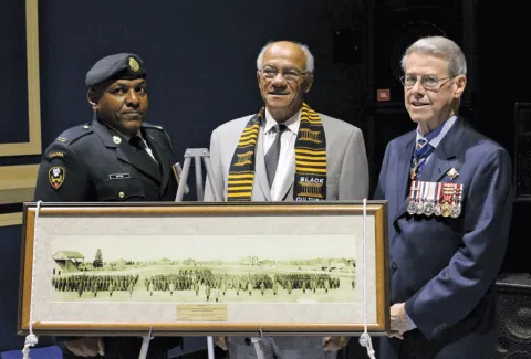 A photo of the No. 2 Construction Battalion on parade grounds in 1916 ipresented to Lt. Gov. Jim Grant, by Dr. Les Oliver, president of the Black Cultural Society. With them is Chief Warrant Officer Steven Milton.