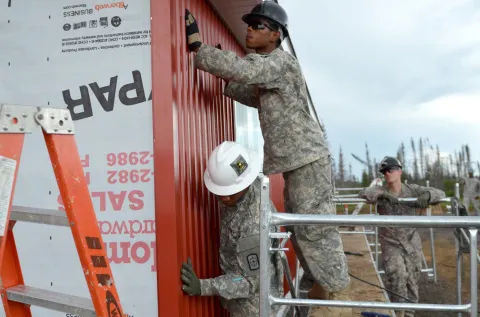 Soldiers with the 808th Engineer Company, Houston, TX, work together to secure siding to the gas hut they are building. PHOTO: Sergeant Crystal L Milton // Les soldats de la 808th Engineer Company de Houston, TX, travaillent ensemble pour sécuriser les côtés de la chambre à gaz qu’ils construisent.. Les soldats américains sont venus de plus de 10 états en août 2014 pour participer à cette opération. PHOTO : Sergent Crystal L Milton