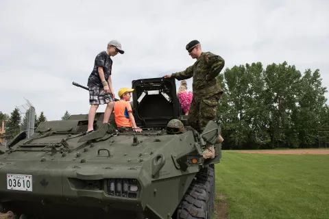 A soldier with 1 Combat Engineer Regiment shows the children of Bon Accord the inside of a Light Armoured Vehicle in Bon Accord, Alberta on June 3, 2017. Photo: Master Corporal Andrew Davis, 3rd Canadian Division Support Base Edmonton. © 2017 DND-MDN Canada
